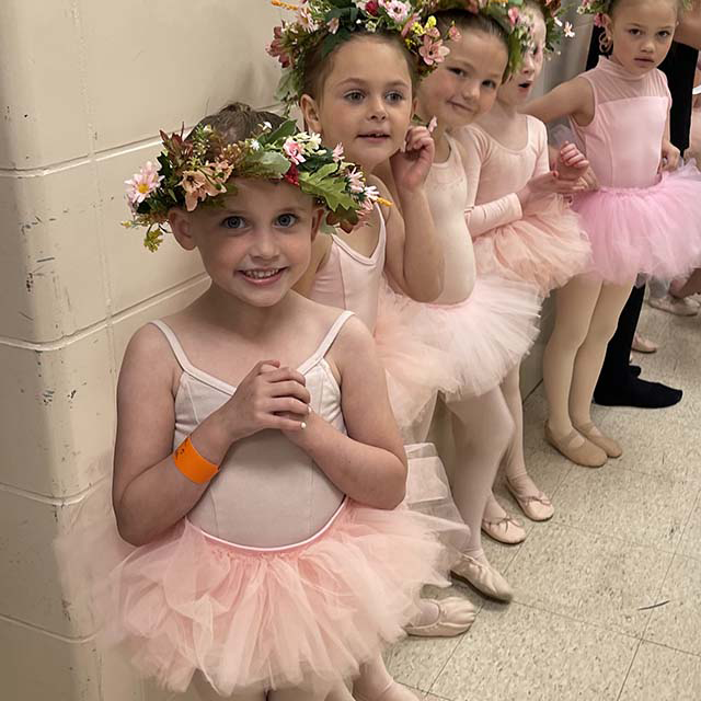 young ballet dancers in pink costumes standing in a line waiting to go on stage